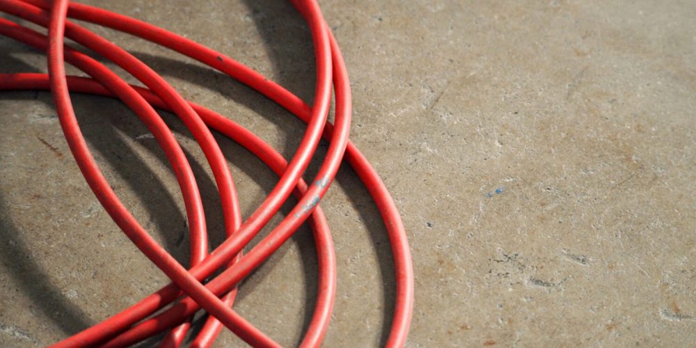 Red color electric power wire cable mess on dirty studio cement floor.